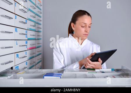 Wunderschöner Apotheker, der Notizblock in der Apotheke verwendet Stockfoto