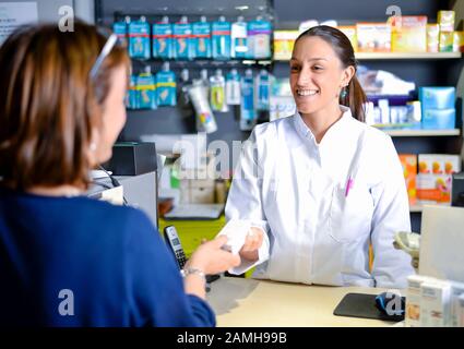 Weibliches Apothekerpersonal berät Kunden über den Drogenkonsum in modernen Apotheken Stockfoto
