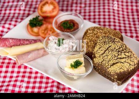 Auf einem roten karierten Tischtuch befindet sich ein Teller mit einem herzhaften Frühstück und einer Tasse schwarzem Kaffee Stockfoto