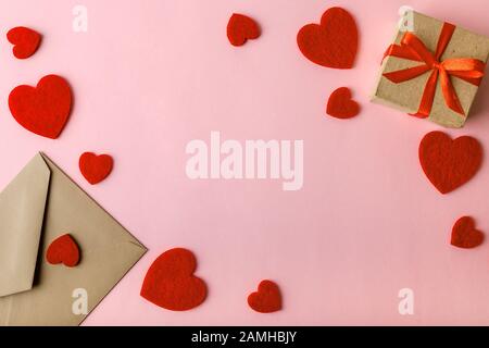 Handarbeit Briefumschlag, Geschenkbox mit rotem Band und valentinsherzen auf pastellrosa Hintergrund. Grußkarte Valentine mit Platz zum Kopieren. Draufsicht. Stockfoto