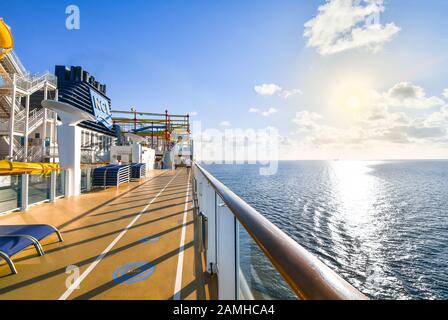 Ein Kreuzfahrtpassagier nutzt den Jogging- und Gehweg auf einem Luxuskreuzfahrtschiff mit einem Schiff in der Ferne auf der Ostsee. Stockfoto