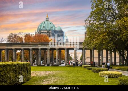 Touristen und Deutsche genießen einen Herbsttag unter buntem Himmel auf der Museumsinsel mit Blick auf den Berliner Dom, während die Blätter orange werden. Stockfoto