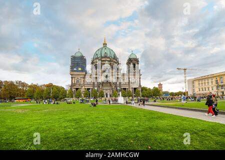 Die Frontfassade des Berliner Doms, wie sich die Öffentlichkeit im Lustgarten an einem teilweise bewölkten Tag im Spätsommer versammelt. Stockfoto