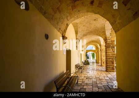 Ein langer, überdachter und gewölbter Portikusflur im historischen Zentrum von Brindisi, Italien, an der Küste der Adria in der Region Apulien. Stockfoto