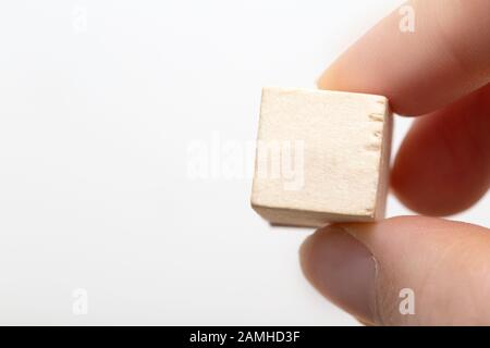 Hand, die einen leeren Holzwürfel hält, der auf weißem Hintergrund isoliert ist Stockfoto