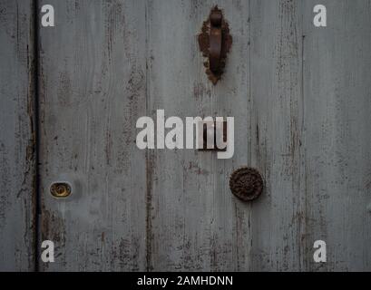 Graublaue alte französische Tür, mit Knocker und Griff, Textur, Hintergrund. Stockfoto