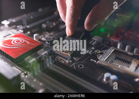 Konzentrieren Sie sich auf den SSD-Steckplatz, geben Sie M.2 mit Unterstützung für NVMe auf der Hauptplatine des Computers ein. Der Techniker installiert ein neues schnelles Laufwerk mit hoher Kapazität und Flash-Chips Stockfoto
