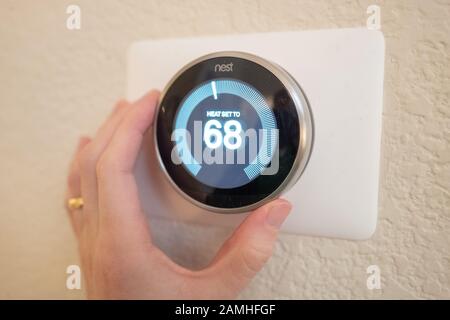 Nahaufnahme eines Mannes, der die Wärmeeinstellung eines Nest Learning Thermostats, eines Internet of Things Geräts von Google Inc, in einem intelligenten Haus in San Ramon, Kalifornien, 17. Dezember 2019 anpasst. () Stockfoto