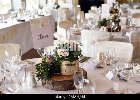 Hochzeitstisch mit Holztablett und Blumen. Stockfoto