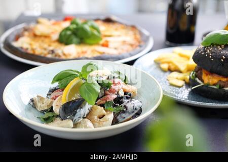 Schwarze Lebensmittel. Burger, Pizza, Pasta, Gerichte mit Aktivkohle. Stockfoto