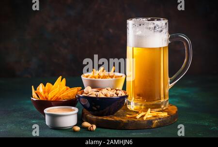 Glas Becher mit Bier mit Schaum und Wasser und Snacks auf einen dunkelgrünen Hintergrund Stockfoto