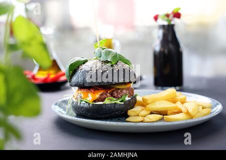 Schwarzer Burger. Ein schmackhafter Burger in schwarzer Rolle. Stockfoto