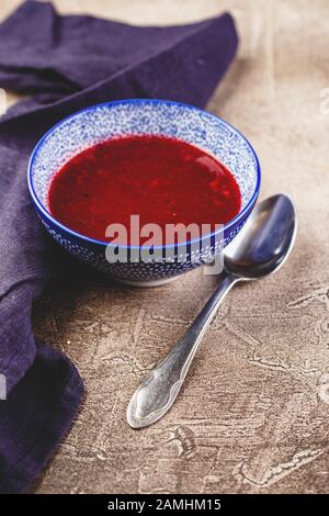 Hausgemachte würzige Süßsoße aus nördlichen Waldbeeren Preiselbeeren und Äpfeln in blauer Schüssel. Stockfoto