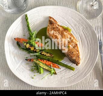 Frisch, vor Ort gekauft Mahi-Mahi mit Kräuterbutterbasil und Petersilie, begleitet von geröstetem Gemüse in Hector's Kitchen in Punta de Mita, Rivie Stockfoto