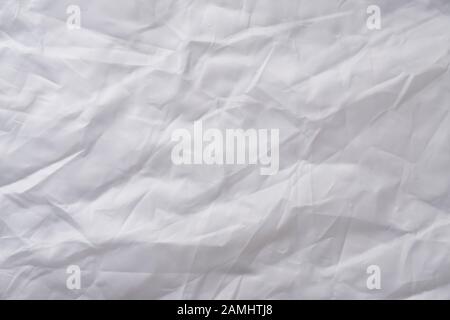 Textur aus zerknittertem weißem Stoff mit blauer Tönung. Weiße Fahne, Reflektor. Kreativer Vintage-Hintergrund Stockfoto