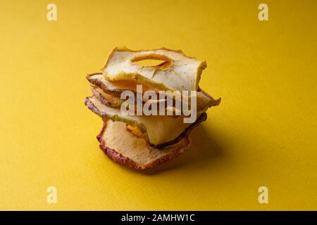 Spänebyramide aus getrockneten Äpfeln auf gelbem Grund und ein Ort für die Beschriftung. Copyspace Stockfoto