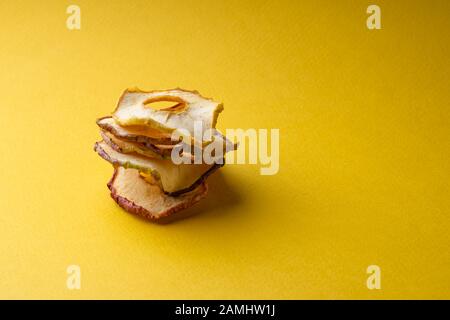 Spänebyramide aus getrockneten Äpfeln auf gelbem Grund und ein Ort für die Beschriftung. Copyspace Stockfoto