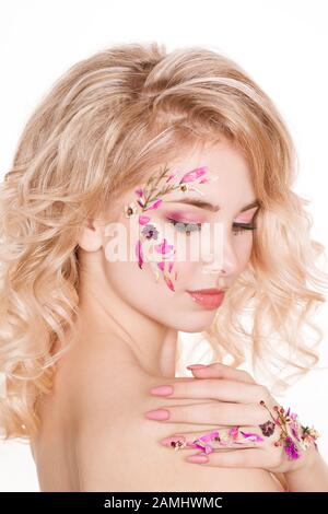 Kosmetik und Maniküre. Nahaufnahme Porträt einer attraktiven Frau mit trockenen Blumen auf ihrem Gesicht, Pastellfarbe Nagel-Design, perfekte Make-up und Haut Stockfoto