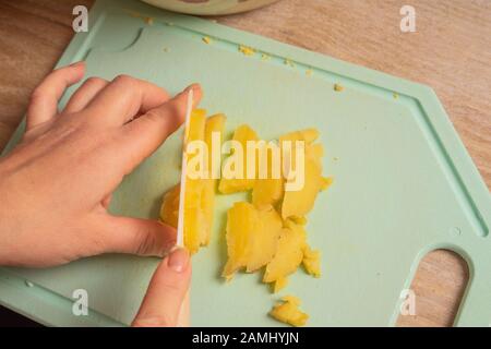 Die Hände des Kochs hacken Eier und Kartoffeln für Salat. Gesundes, natürliches vegetarisches Essen Stockfoto