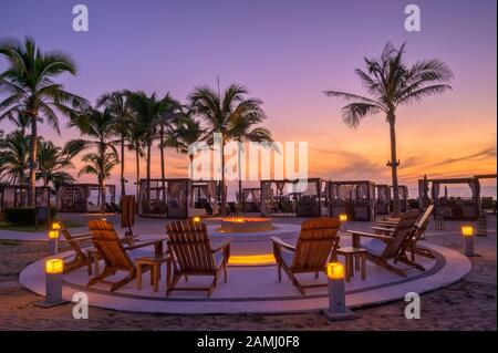 Sonnenuntergang rund um die Feuerstelle am Strand im Mozzamare Beach Club des Marival Resort in Nuevo Vallarta, Riviera Nayarit, Mexiko. Stockfoto