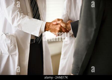 3/4-Ansicht von zwei Personen, die die Hände schütteln. Stockfoto