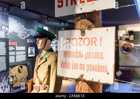 Warnschilder in tschechischer Sprache an einem Stacheldrahtzaun in einem Museum neben einer Schaufensterpuppe mit einer Militäruniform der sowjetischen Ära. Stockfoto