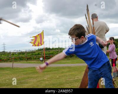 Ein kleiner Junge, der lernt, eine Axt auf ein lebendiges Geschichtsereignis zu werfen Stockfoto