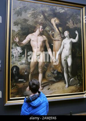 Ein kleiner Junge betrachtet das Kunstwerk "der Fall des Menschen" von Cornelis Cornelisz van haarlem im Rijkmuseum, Amsterdam, Niederlande. Stockfoto