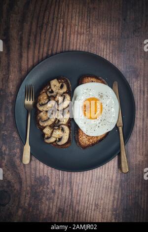 Pilze auf Toast und gebratenes Ei auf Toast. Mit einem Sauerteigbrot mit Kastanienpilzen Stockfoto