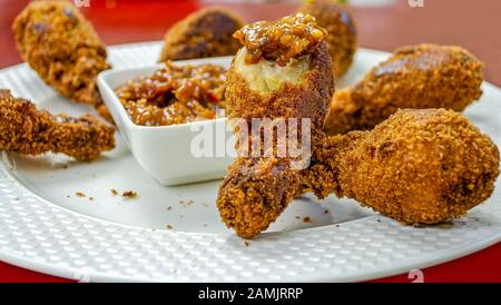 Nahaufnahme von heißem und knusprigem, halbgebittenem Hühnchenfleisch, das in Sauce getaucht ist und verzehrt werden kann. Stockfoto