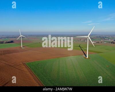 Luftbild von Windkraftanlagen auf landwirtschaftlichen Feldern während des blauen Wintertags. Energieerzeugung mit sauberer und erneuerbarer Energie. Stockfoto