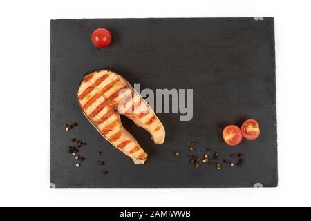 Gebratenes Lachssteak mit Zitrone auf Schiefer. Auf weissem Hintergrund Stockfoto