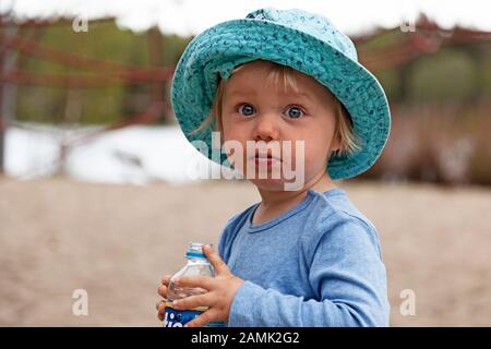 Umea, Norrland Schweden - 7. Juni 2019: Kleiner besorgter Junge trinkt aus Plastikflasche Stockfoto