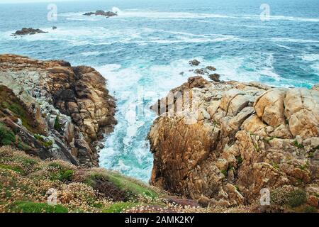 Meereswellen, die auf den Felsen einer Klippe in einer Coruna, spanien, brechen Stockfoto