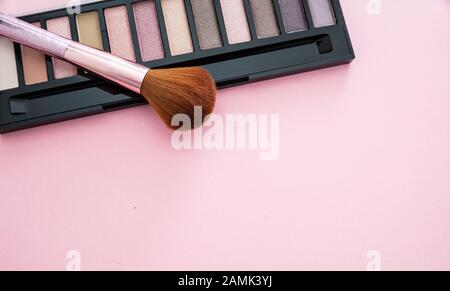 Augenschatten setzen neutrale Farben und bürsten vor rosafarbenem Hintergrund, Draufsicht. Professionelle Werkzeuge für Make-up, Beauty-Salon, Kosmetikkonzept Stockfoto