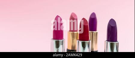 Lippenstifte setzen bunt vor rosa Hintergrund, Nahansicht. Leuchtende Farben Lippenglanz, Kosmetik, Makeup-Konzept Stockfoto