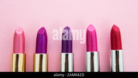 Lippenstifte setzen bunt vor rosa Hintergrund, Nahansicht. Leuchtende Farben Lippenglanz, Kosmetik, Makeup-Konzept Stockfoto