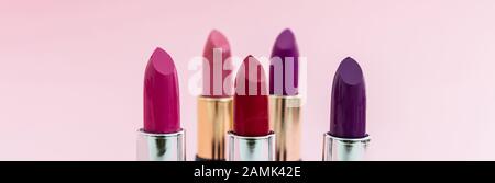 Lippenstifte setzen bunt vor rosa Hintergrund, Nahansicht. Leuchtende Farben Lippenglanz, Kosmetik, Makeup-Konzept Stockfoto