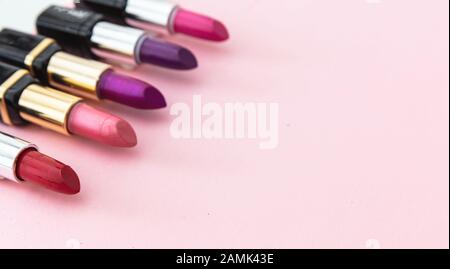 Lippenstifte setzen bunt vor rosa Hintergrund, Nahansicht. Leuchtende Farben Lippenglanz, Kosmetik, Makeup-Konzept Stockfoto