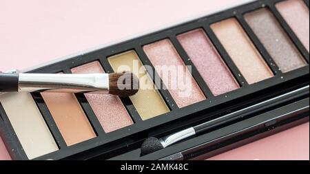 Eyeshadows pallete setzen neutrale Farben und bürsten vor rosafarbenem Hintergrund, Nahaufnahme. Professionelle Werkzeuge für Make-up, Beauty-Salon, Kosmetikkonzept Stockfoto