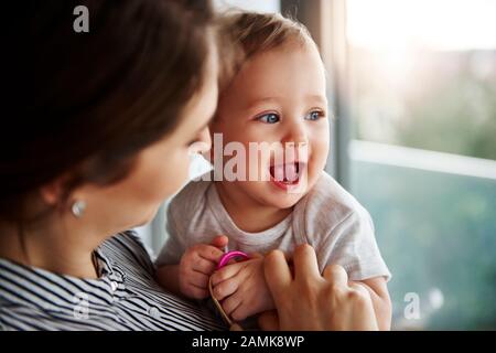 Liebevolle Mutter umarmte ihr liebenswerliches Babymädchen Stockfoto