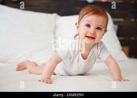 Portrait des Babys, das auf dem Bett krabbelt Stockfoto