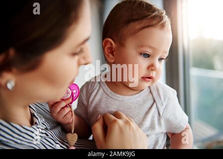 Liebevolle Mutter, die ihr liebenswerliches Mädchen hält Stockfoto