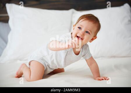 Glückliches Baby, das auf dem Bett krabbelt Stockfoto