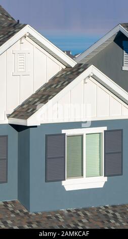 Vertikale grau-weiße Hausfassade mit Fensterläden Stockfoto