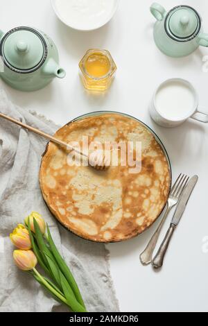 Schmackhaftes traditionelles russisches Frühstück, Pfannkuchen, Blini, saure Sahne, Milch, Honig auf dem Teller. Draufsicht. Traditionelle Bedienung. Pfannkuchenwoche. Shrovetide. Vertic Stockfoto