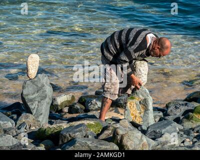 Balanced Rock artist Erstellen ausgewogene Skulpturen aus Stein unser Strand Kies auf St Ives, Cornwall, England, Großbritannien Stockfoto