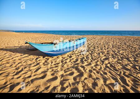 Altes Fischerboot am leeren Strand von ae bei Sonnenuntergang, Sri Lanka. Stockfoto