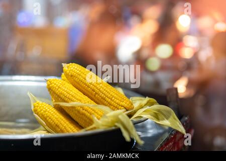Frisch gedämpfter Mais in einer Metallschale zum Verkauf auf dem Straßenmarkt in der chinesischen Kleinstadt Stockfoto