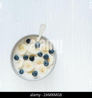 Gesundes Frühstück mit Joghurt und Hafergranola, Bananen und Blaubeeren in der Schüssel. Mit Kopierraum. Leckere Blätterschüssel. Vegane Rohkost. Se Stockfoto